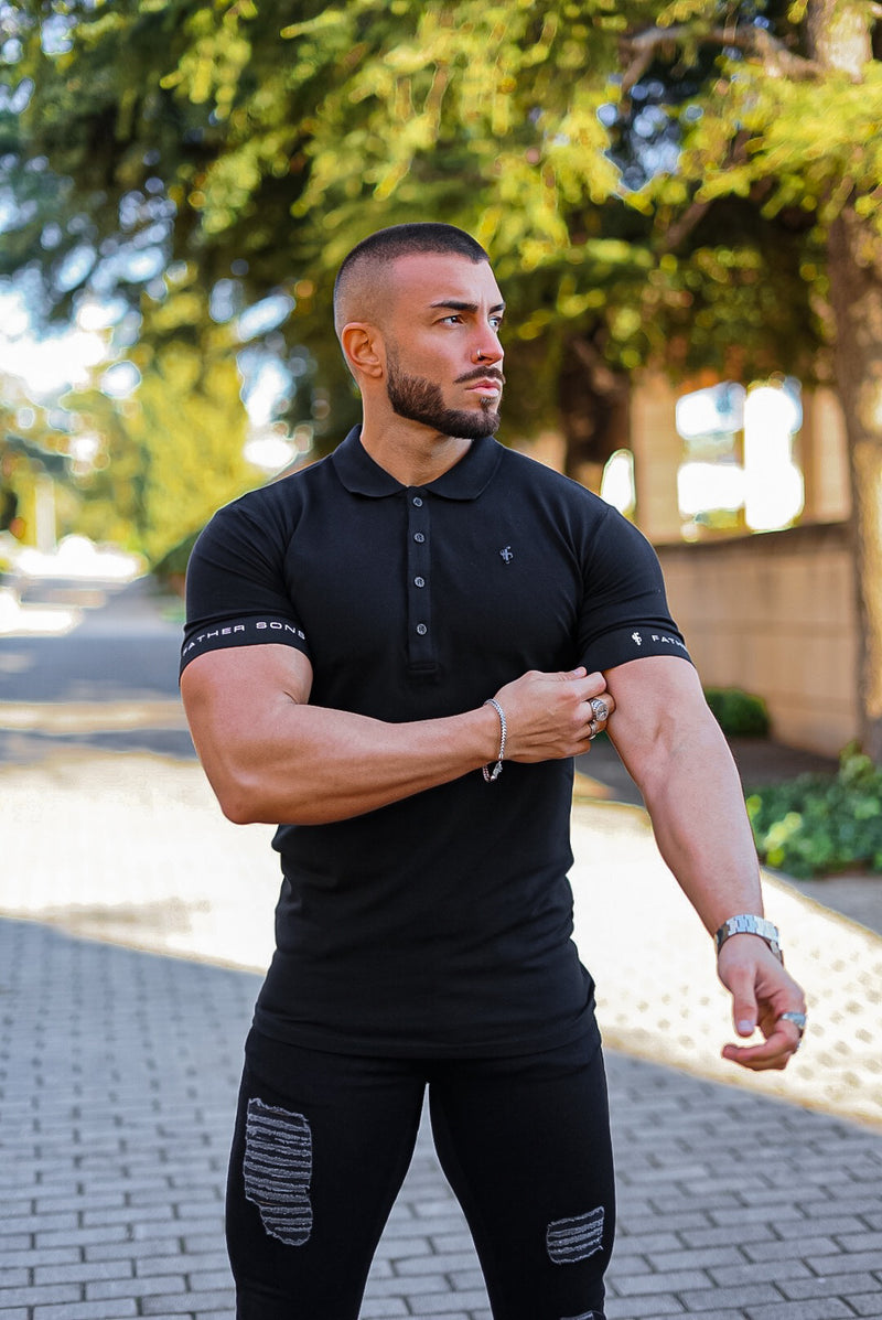 Klassisches schwarzes Poloshirt von Father Sons mit elastischem FS-Logo auf den Ärmeln und schwarzem Metallemblem – FSH631